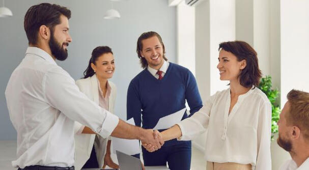 The image depicts a group of people smiling and shaking hands, satisfied with negotiated settlement agreement
